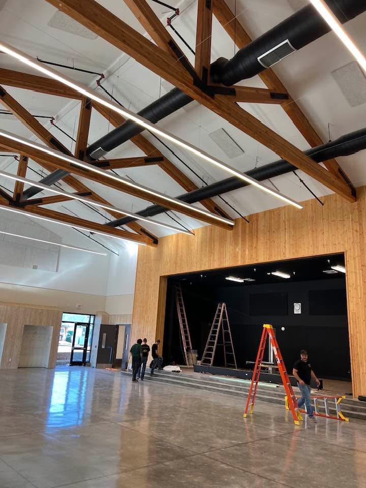 Finished auditorium with stage, wood beams, and modern lighting